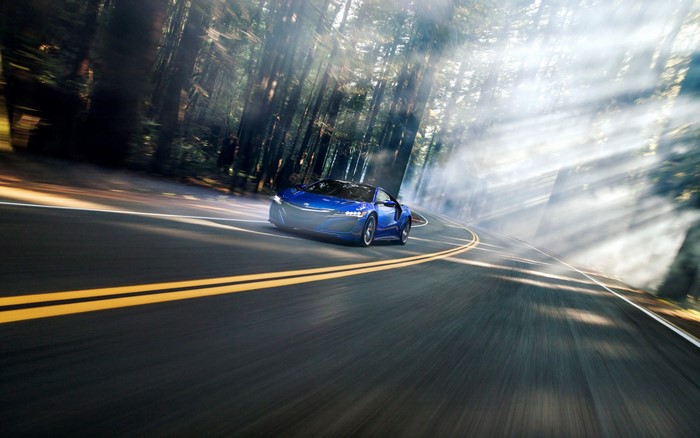Blue Acura NSX driving on a forest road with sunbeams