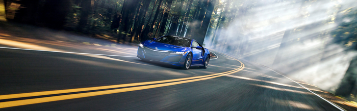 Blue Acura NSX driving on a misty forest road