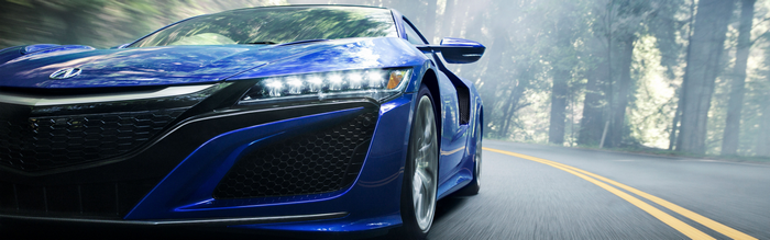 Blue Acura NSX sports car driving on a misty forest road