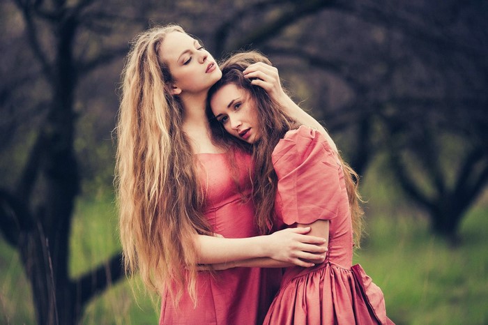 Two women in pink dresses embracing outdoors