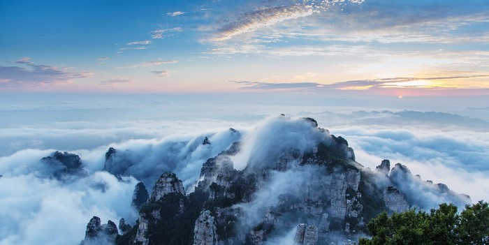Misty mountain peaks at sunrise with clouds