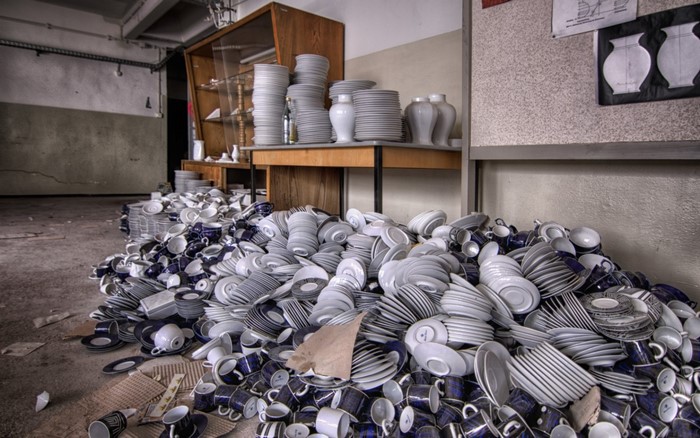 Abandoned room with piles of ceramic plates and mugs