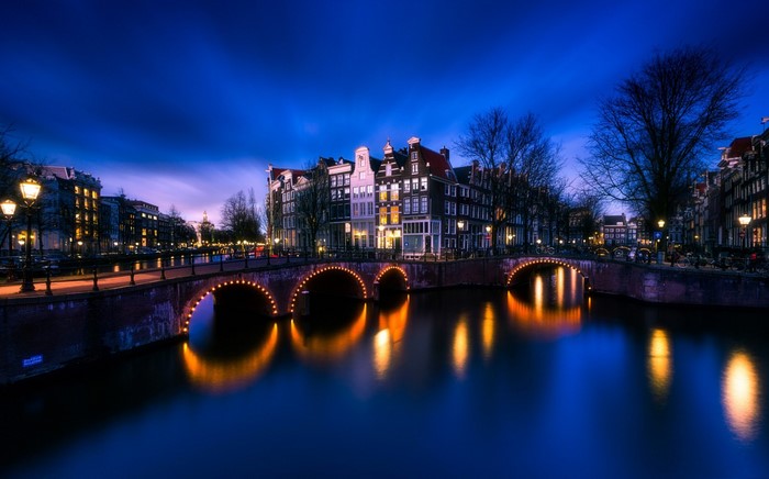 Amsterdam canal bridge at night with reflections