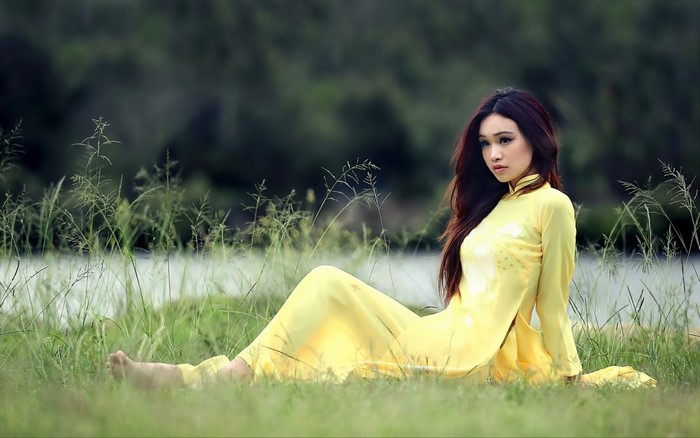 Woman in yellow dress sitting in grass