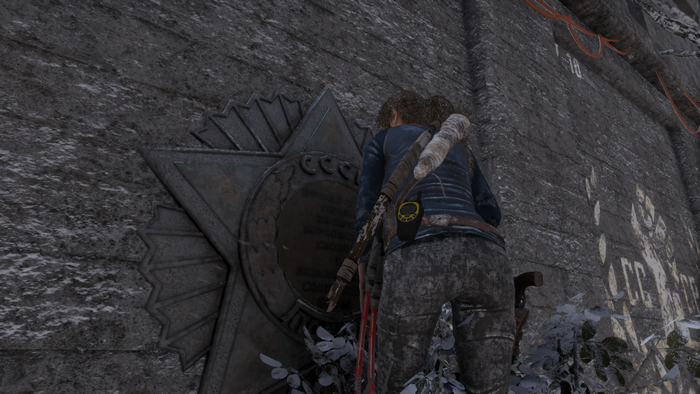 Lara Croft from Rise of the Tomb Raider examining a Soviet star emblem
