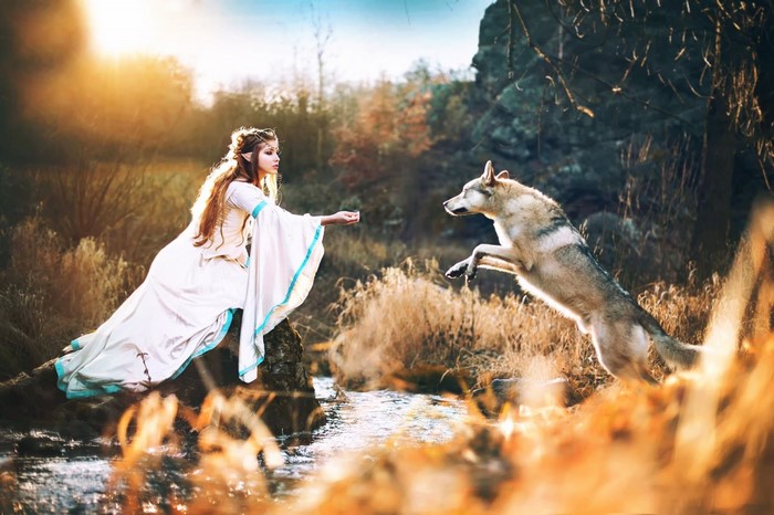 Elf woman with wolf by stream in autumn
