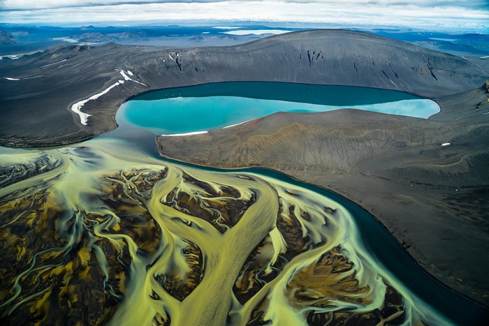 Aerial view of braided river delta and turquoise lake in Iceland