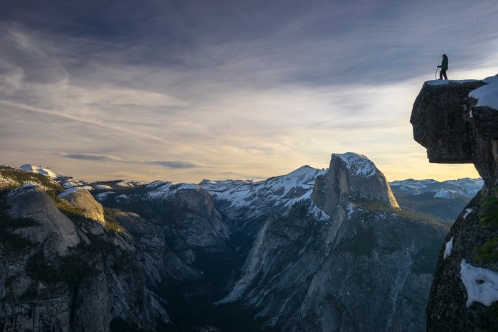 Man on cliff overlooking Yosemite Valley with Half Dome