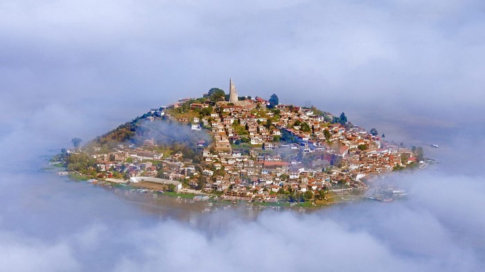 Island village on a hill surrounded by mist and water