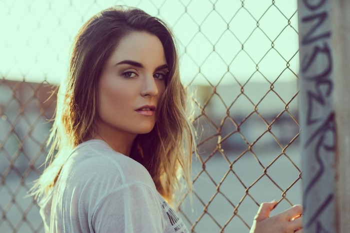 Woman with long brown hair by a fence
