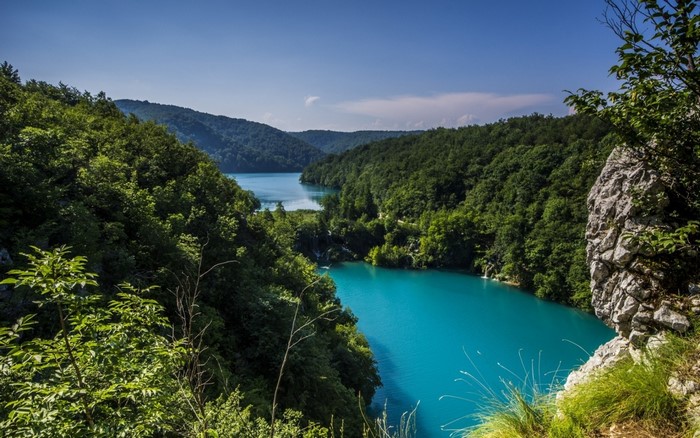 Turquoise lake surrounded by green forest and rocky cliffs
