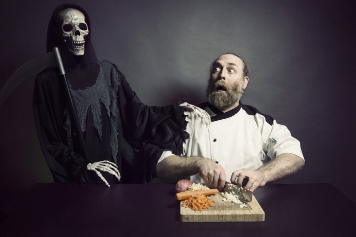 Grim Reaper startling a chef while he chops vegetables