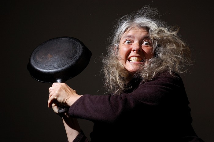 Woman with gray hair holding a cast iron skillet