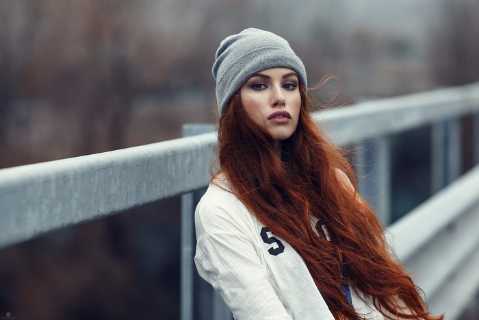 Woman with red hair wearing a beanie and white shirt