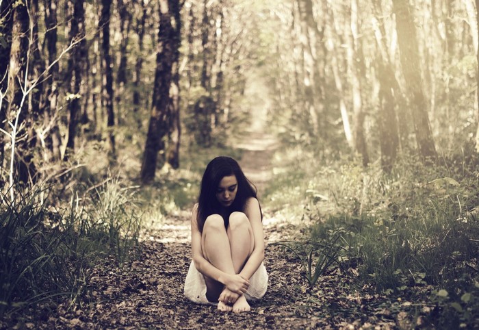 Woman Sitting Alone on Forest Path at Sunrise
