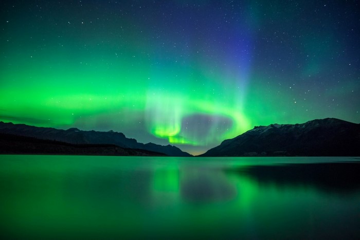 Aurora Borealis over a lake with mountains