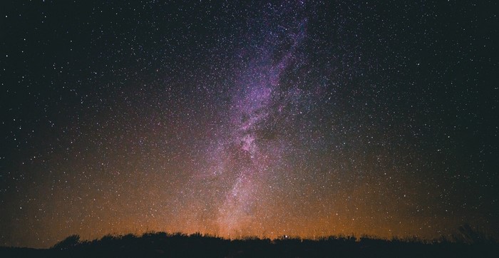 Milky Way galaxy over a dark landscape