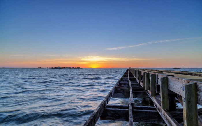 Sunset over the ocean with a wooden pier