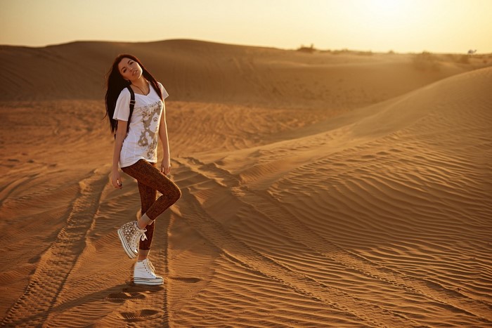 Woman posing in a desert with sand dunes