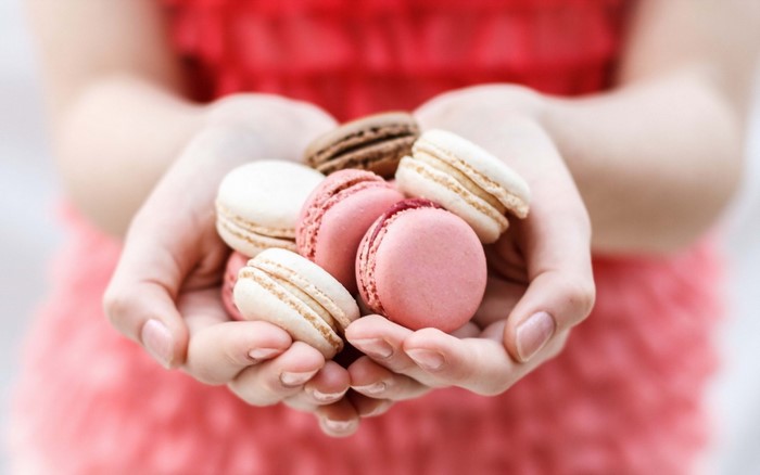 Hands holding colorful macarons
