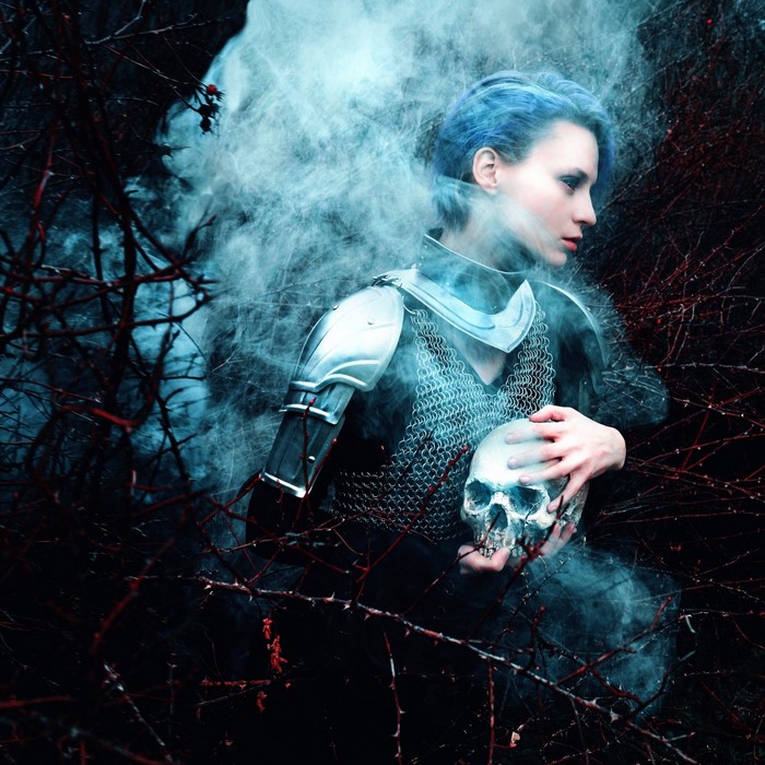 Woman in armor holding a skull with blue hair