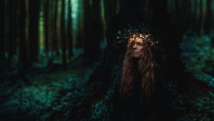 Woman with a crown of lights in a dark forest