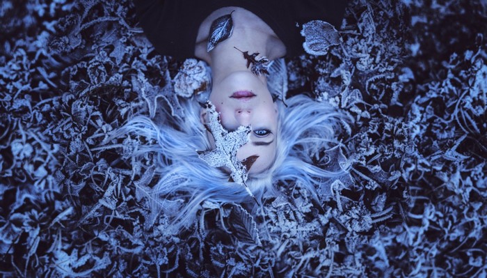 Woman with white hair lying on frosted leaves
