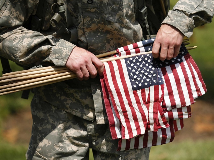 Soldier holding American flags and wooden poles