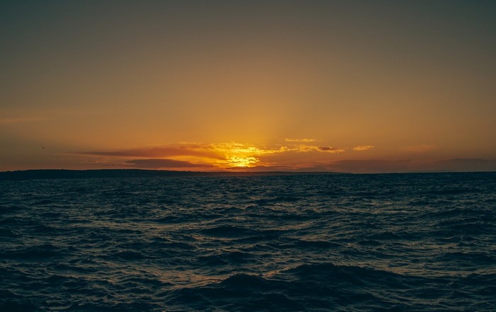 Sunset over the ocean with waves and distant land