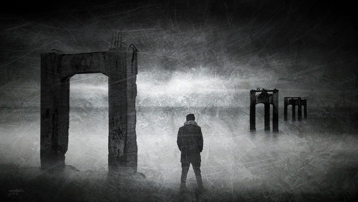 Man standing before ruined structures in fog