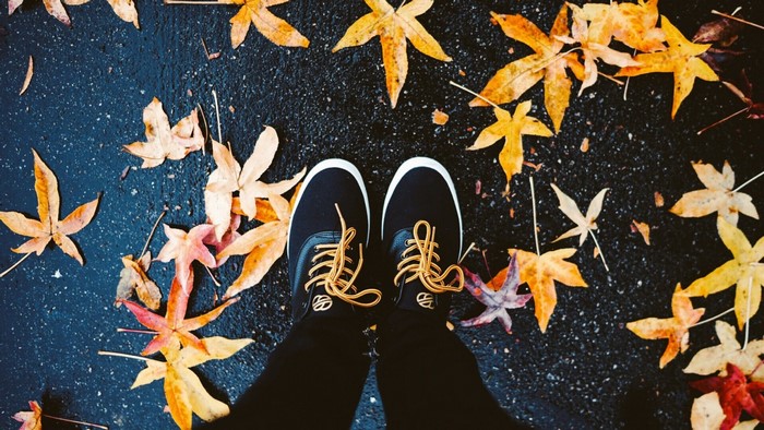Feet in shoes surrounded by fall leaves