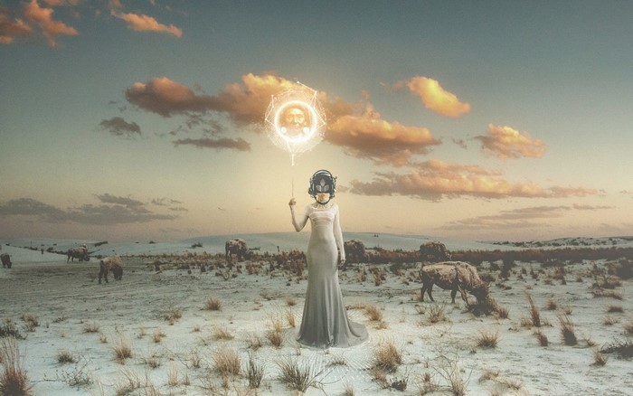 Woman with futuristic helmet holding a glowing orb in a desert landscape