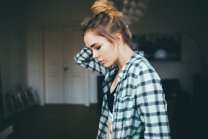 Woman with blonde hair in a bun wearing a plaid shirt