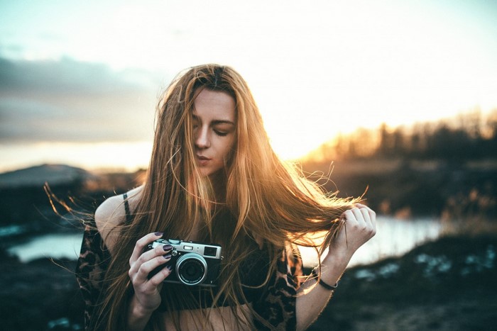 Woman holding a camera outdoors at sunset