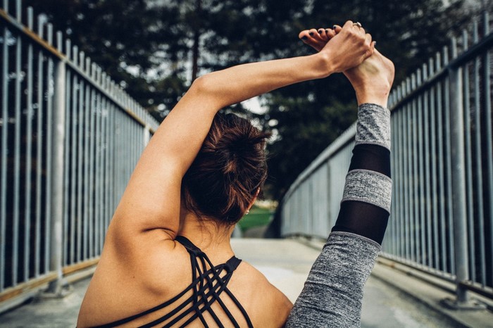 Woman stretching her leg and arm outdoors