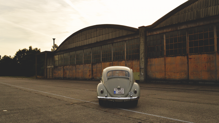 Volkswagen Beetle parked in front of an old hangar