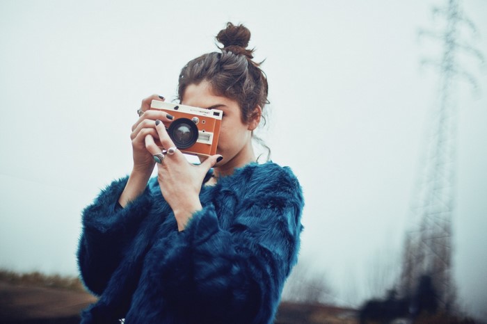 Woman in blue fur coat holding an orange camera