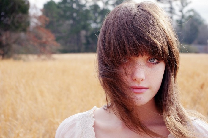 Young woman with brown hair and blue eyes in a field