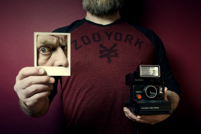 Man holding Polaroid camera and photo of his eye