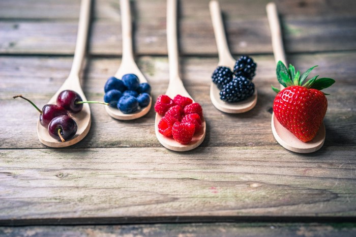 Wooden spoons filled with assorted berries and fruits