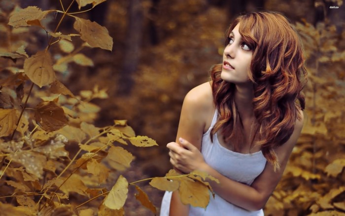 Woman in white tank top among autumn leaves