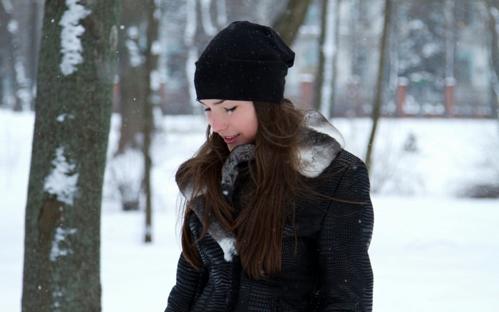 Young woman in a black beanie and coat in the snow