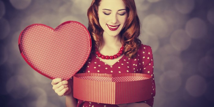 Woman in red polka dot dress holding heart-shaped box