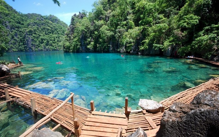 Crystal clear turquoise lagoon with wooden walkways and lush green mountains