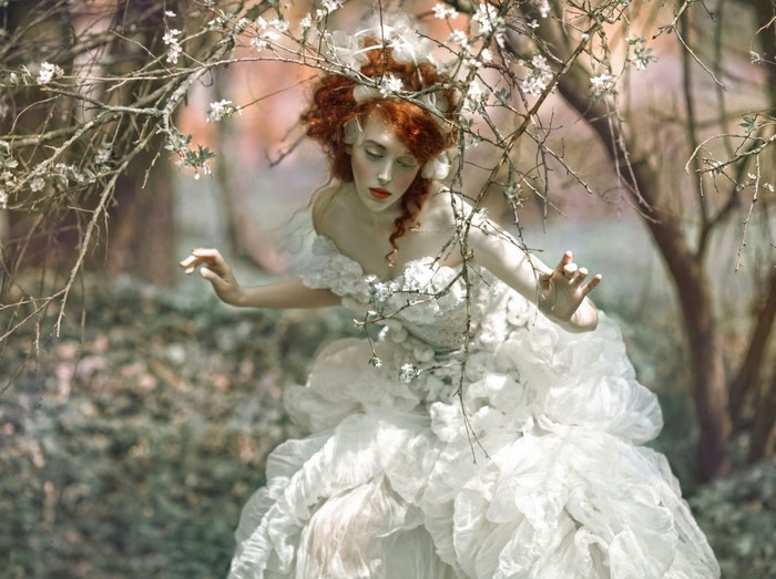 Woman in white dress among flowering branches
