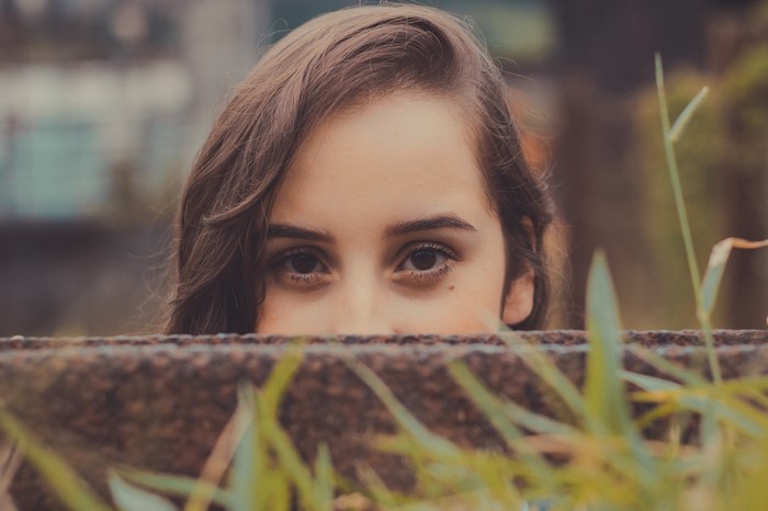 Close up of a young woman's eyes peeking over a wall