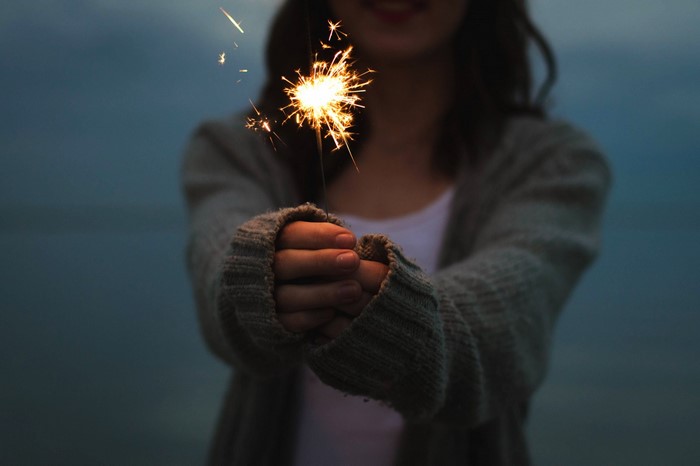 Woman holding a sparkler at dusk