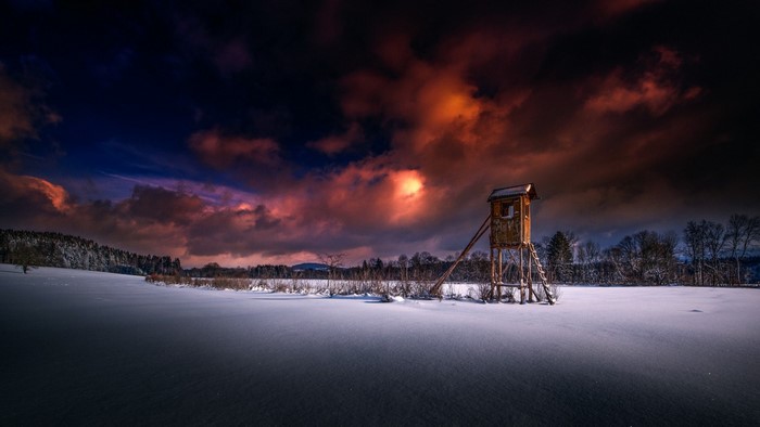 Wooden hunting blind in a snowy landscape at sunset