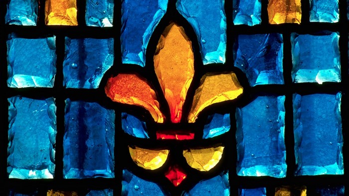 Close-up of a blue and yellow stained glass window with a fleur-de-lis.