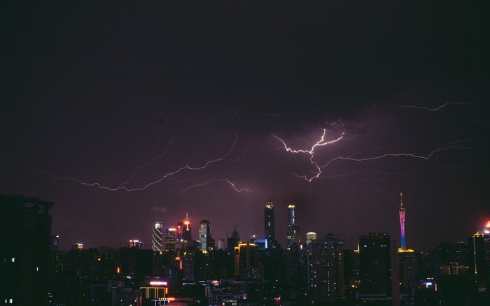 Lightning strikes over a city skyline at night